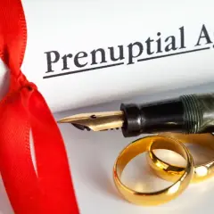 Rozdzielność majątkowa u notariusza: ile kosztuje podpisanie aktu? Złote obrączki, pióro i dokument "Prenuptial Agreement" symbolizują tę decyzję.