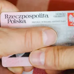 Dłonie trzymają polski dowód osobisty. Widoczny jest numer dowodu osobistego.