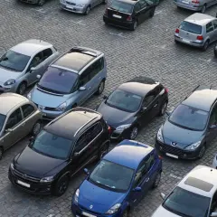 Na parkingu stoi wiele samochodów. Kto to komisant? Może to osoba, która właśnie kupuje lub sprzedaje jeden z tych pojazdów.