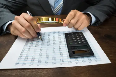 Kontrola dokumentów finansowych z lupą i kalkulatorem. Kara porządkowa ordynacja podatkowa.