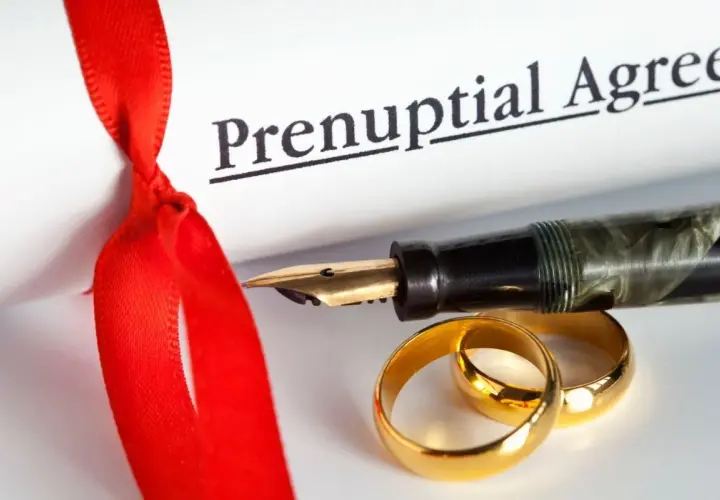 Rozdzielność majątkowa u notariusza: ile kosztuje podpisanie aktu? Złote obrączki, pióro i dokument "Prenuptial Agreement" symbolizują tę decyzję.