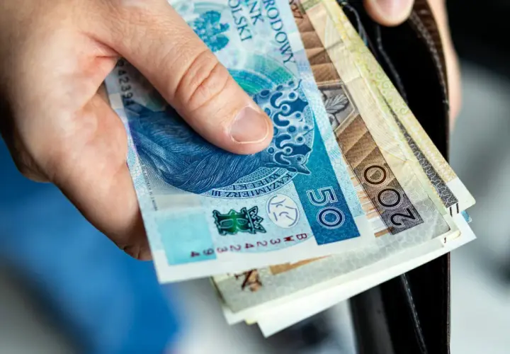 Dłoń trzyma polskie banknoty: 50 zł i 200 zł. Zastanawiasz się, ile kosztuje akt zgonu?