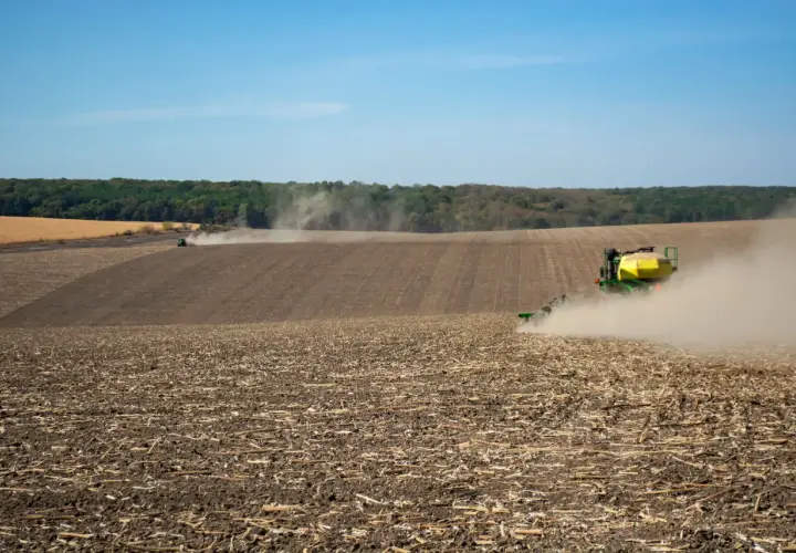 Traktor sieje na polu, wzbijając kurz. Czy umowę dzierżawy trzeba zgłosić do gminy? Pytanie to nurtuje rolników.