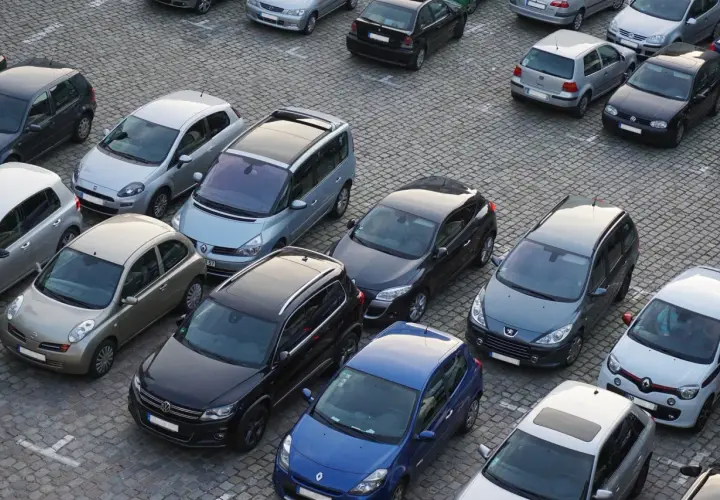 Na parkingu stoi wiele samochodów. Kto to komisant? Może to osoba, która właśnie kupuje lub sprzedaje jeden z tych pojazdów.