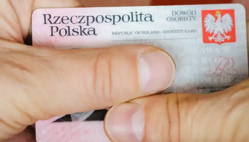 Dłonie trzymają polski dowód osobisty. Widoczny jest numer dowodu osobistego.