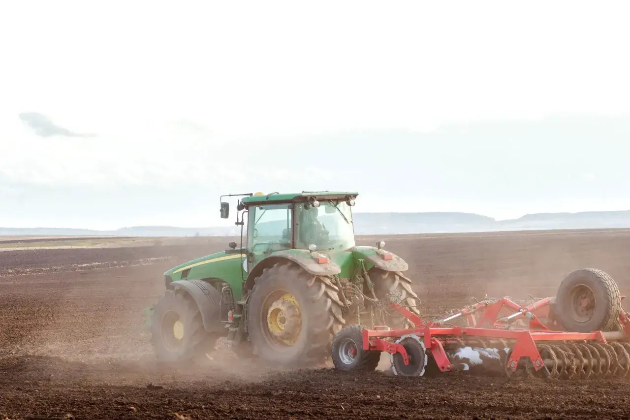 Zielony traktor orze pole. To symbol przekazania gospodarstwa rolnego, które pozwala na opiekę nad rodzicami i dalszy rozwój.