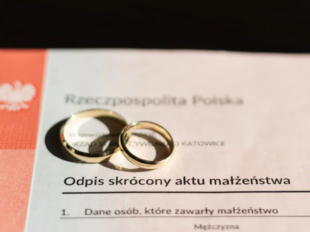 Złote obrączki na odpisie skróconym aktu małżeństwa. Zastanawiasz się, ile kosztuje akt małżeństwa? Dokument z pieczęcią Urzędu Stanu Cywilnego w Katowicach.