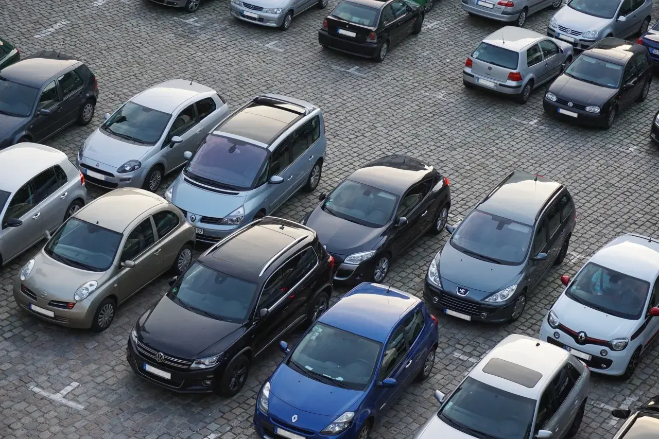 Na parkingu stoi wiele samochodów. Kto to komisant? Może to osoba, która właśnie kupuje lub sprzedaje jeden z tych pojazdów.
