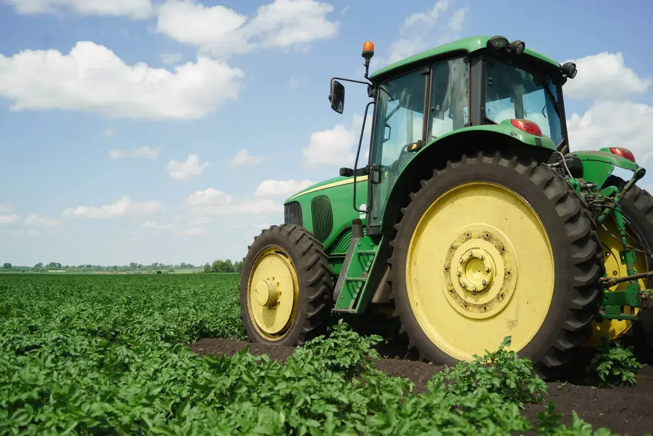 Zielony traktor na polu ziemniaków. Nowy właściciel, który nie jest rolnikiem, dziedziczy ziemię rolną i musi nauczyć się obsługi maszyny.