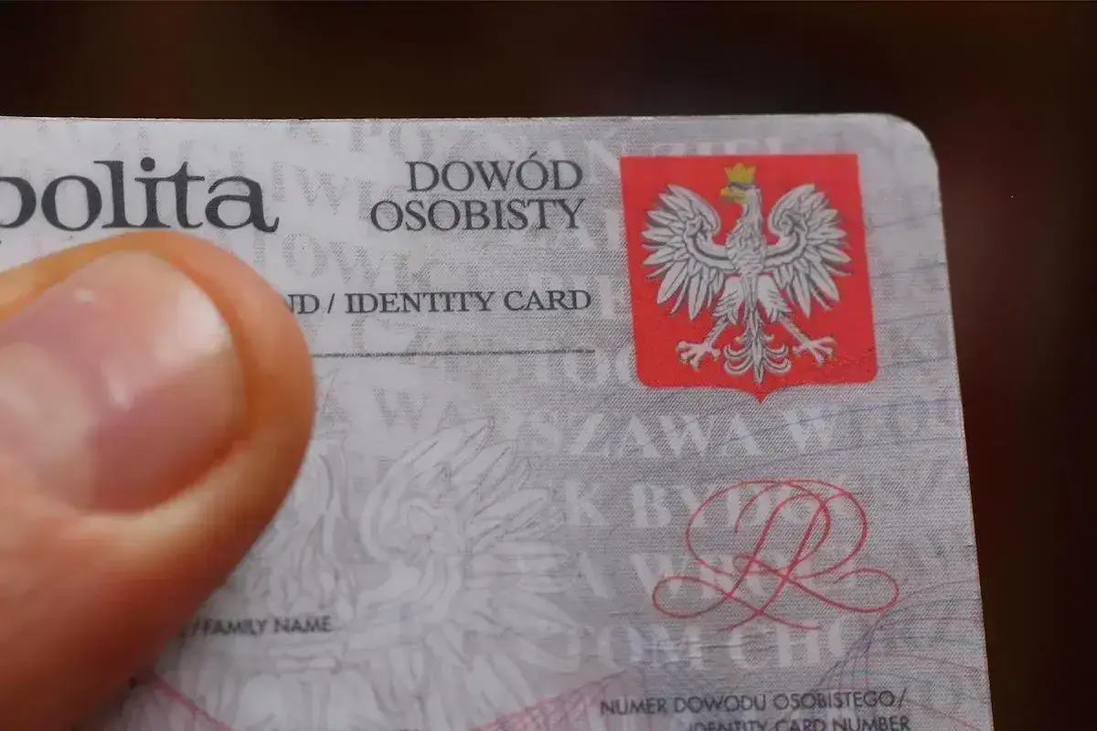 Zgubiony dowód osobisty. Kciuk zasłania część dokumentu z godłem Polski.