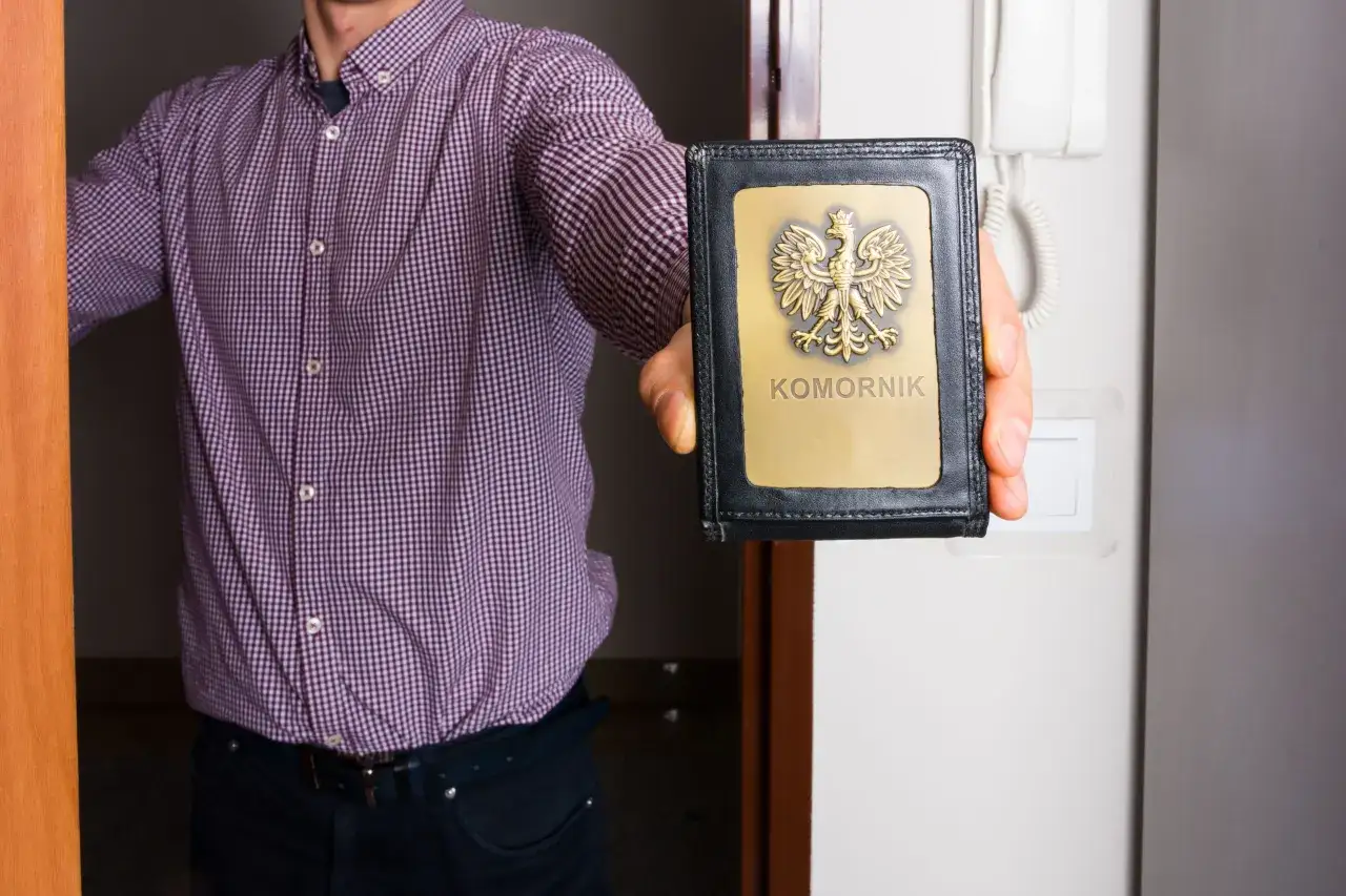 Mężczyzna w koszuli pokazuje legitymację komornika. Czy komornik może zająć umowę zlecenie? To pytanie, na które odpowiedź może być złożona.