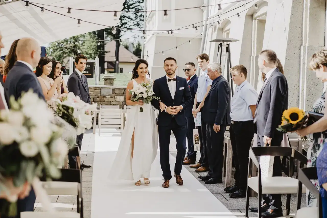 Para młoda idzie do ołtarza. Zastanawiasz się, ile kosztuje akt małżeństwa? Ceremonia odbywa się na zewnątrz, przy pięknej pogodzie.