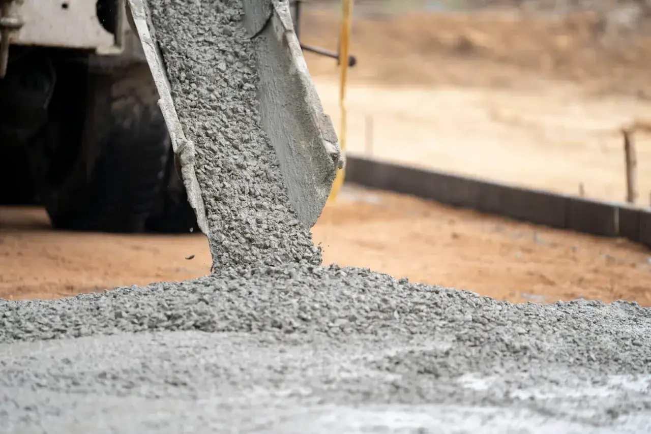 Beton wylewany z gruszki na ziemię. Może to być kara za utwardzenie działki rolnej.